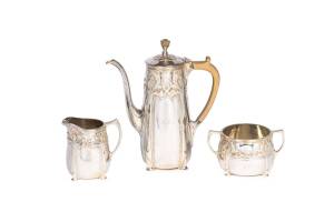 A George V sterling silver three piece coffee set by Charles & Richard Comyns,  London 1920 made for Tiffany & Co; with engraved initials "JH", comprising a coffee pot, cream jug and sugar bowl all with applied scroll decoration; the pot 22cm high, 1,275 