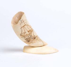 A scrimshaw whale's tooth on whale's tooth base engraved with tall ship and whaling boat on reverse