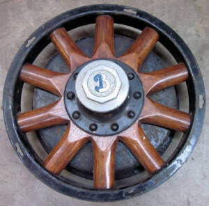 Vintage car wooden spoked wheel with "B", on the hub; old metal tractor seat, and an antique farm winch.