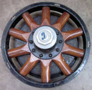 Vintage car wooden spoked wheel with "B", on the hub; old metal tractor seat, and an antique farm winch.