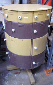 Unusual drum shaped revolving metal cabinet, (4) rows of graduated drawers with old porcelain handles, painted in two tone brown and khaki on a wooden base with makers plaque "Metters Ltd. Sydney N.S.W.". 125cm tall, Good condition.