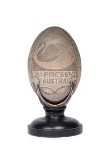 A carved emu egg titled "A Present from Australia" decorated with kangaroos, Aboriginal, swans, kookaburra and snake etc, late 19th century mounted in silver plate with turned timber base