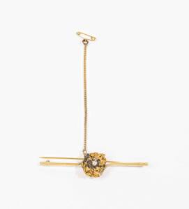 A gold bar brooch set with a brilliant cut diamond within a gold nugget, unmarked