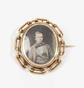 A Victorian portrait brooch set with a daguerreotype of a young man within a chain link mount, circa 1880