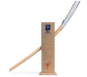 1994 WINTER OLYMPICS MINI TORCH, 60cm long, wood and metal engraved with 6 winter events. Accompanied by wooden display stand, 31cm tall, featuring Lillehammer logo and torch runner.