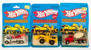 HOTWHEELS: 1980s Group of ‘Workhorses’ Including Phone Truck (5906) – White; And, Trash Truck (3912) – Orange; And, Construction Crane (3254) – Yellow. All mint and unopened on original cardboard blue packaging. (25 items)