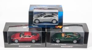 MINICHAMPS: 1:43 Group of Aston Martin Model Cars Including 2003 Aston Martin DB9 (137324) – Red, Aston Martin V12 Vanquish (137222) – Green; And, ‘James Bond’ Aston Martin V12 Vanquish (45125) – Grey.  All mint in original perspex display case. (3 items)