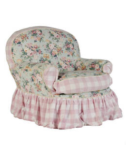 An upholstered armchair covered in pink and floral pattern fabric