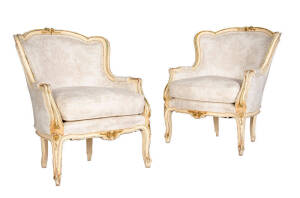 A pair of antique French bergere armchairs. Cream finish with gilded highlights upholstered in beige and cream fabric.&nbsp;