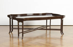 COFFEE TABLE: Large shaped gallery top with brown lacquer finish on a double cross stretcher base. 140 x 89 x 50cm