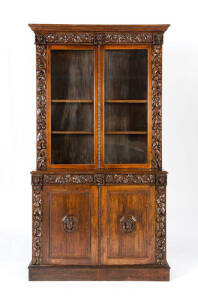 BOOKCASE: English oak & glass with full length carved corbels & facemask decoration, 19th century. Width 123cm, Height 228cm