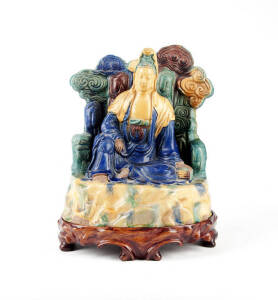 A large blue, green, brown and yellow glazed earthernware figure of a seated Guanyin
