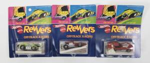 HOTWHEELS: 1973 group of Redline ‘Revvers’ including Jettin’ Vette (6997) – Enamel Red; and, Stingin’ Thing (6987) – Enamel Lime Green; And, Buzzin’ Bomb (6986) - Enamel Red. All mint and unopened in original rectangular blue blister pack. (3 items)