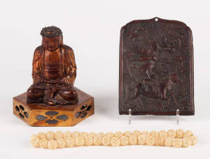 A Japanese lacquer figure of seated Buddha on a reticulated base 15cm high, a Tibetan repousse copper plaque 15cm high and a string of intricately carved bone beads approx. 48cm long
