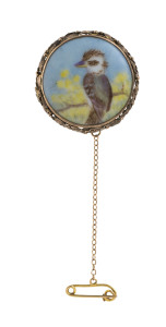 A kookaburra brooch, hand painted porcelain set in gold mount adorned with gumnuts and leaves reverse signed "F. WILSON, 1919"