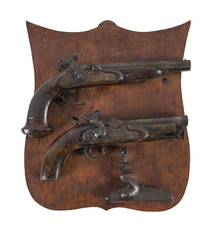 An antique pistol display comprising two percussion cap pistols and a flintlock (only) mounted on board with inscription verso