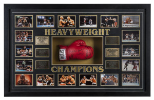 "HEAVYWEIGHT CHAMPIONS" framed display comprising 18 action photographs and six engraved brass plaques surrounding a full-sized boxing glove signed by the six champions: Muhamad Ali, Joe Frazier, George Foreman, Mike Tyson, Lennox Lewis and Evander Holyfield. Overall 80 x 128cm and most impressive!.