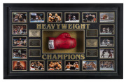 "HEAVYWEIGHT CHAMPIONS" framed display comprising 18 action photographs and six engraved brass plaques surrounding a full-sized boxing glove signed by the six champions: Muhamad Ali, Joe Frazier, George Foreman, Mike Tyson, Lennox Lewis and Evander Holyfi