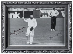 A framed black & white photograph of Allan Border holding his bat in the air (Adelaide Test Match v New Zealand, December 1987) acknowledging the applause of the crowd at the moment he passed Don Bradman's test run total of 6996 runs. With the original signatures of Bradman & Border. Overall 16 x 20.5cm.Border was the only cricketer to have scored 150 in each innings of a Test match. He retired as the leading run scorer in history, with a whopping 11,174 from 156 appearances.Provenance