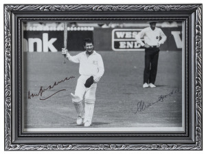 A framed black & white photograph of Allan Border holding his bat in the air (Adelaide Test Match v New Zealand, December 1987) acknowledging the applause of the crowd at the moment he passed Don Bradman's test run total of 6996 runs. With the original si
