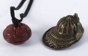A Japanese brass Samurai helmet netsuke; together with a cinnabar lacquered button, Meiji period, the helmet 5cm long