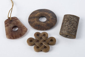 Three Chinese carved jade pendants and a pi disc, the disc 6cm diameter