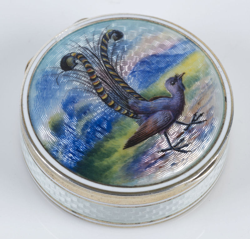 A sterling silver pill box with enamel lyrebird decoration, circa 1900, stamped "925, S & Co. n" with triangle mark, 4.5cm diameter