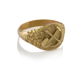 An Australian gold miner's ring with crossed pick and shovel, mid 19th century, stamped "18" with crown mark and monogrammed "E.F.", ​6 grams