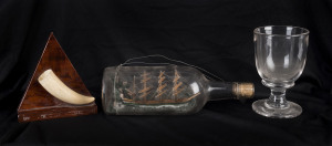 A model ship in a bottle, whales tooth plaque and antique ale glass, 19th and 20th century, the bottle 26cm long