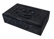 An ebonized wooden box, carved with Maori decorations and with inlaid paua shell eyes, late 19th century,&nbsp;