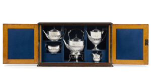 TEESDALE SMITH Family sterling silver tea service, maker's mark "E.H.", London, circa 1888, engraved with the family crest and motto, housed in original plush fitted oak cabinet box, with Sydney retailers plaque "FAVELLE & ROBERTS, SYDNEY". The cabinet 46cm high, 78cm wide, 23cm deep. the spirit kettle 38cm high, total weight of the service (includes handles) 3160 grams. PROVENANCE: Teesdale Smith Family Collection