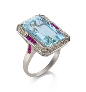A white gold contemporary cluster ring featuring a large rectangular pale blue acquamarine surrounded by brilliant cut diamonds and rubies, 8.8 grams