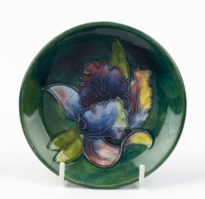 MOORCROFT "Orchid" pattern dish on green ground, stamped "Moorcroft, Made In England", and with paper label "By Appointment, W. Moorcroft, Potters To Late Queen Mary", 12cm diameter