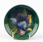 MOORCROFT "Orchid" pattern dish on green ground, stamped "Moorcroft, Made In England", and with paper label "By Appointment, W. Moorcroft, Potters To Late Queen Mary", ​12cm diameter