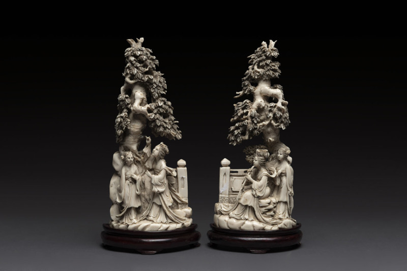 A pair of Chinese carved ivory figures on wooden stands, 19th/20th century, each carved from a solid piece, two character mark to bases, 29cm high overall