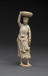 A carved ivory figure of a peasant carrying a basket of corn, 19th century, 20cm high