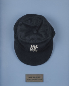 RAY BRIGHT'S VICTORIAN STATE TEAM CAP, navy blue wool with the VCA logo embroidered to front; made by Phillip Joseph and signed on the label. Attractively framed.