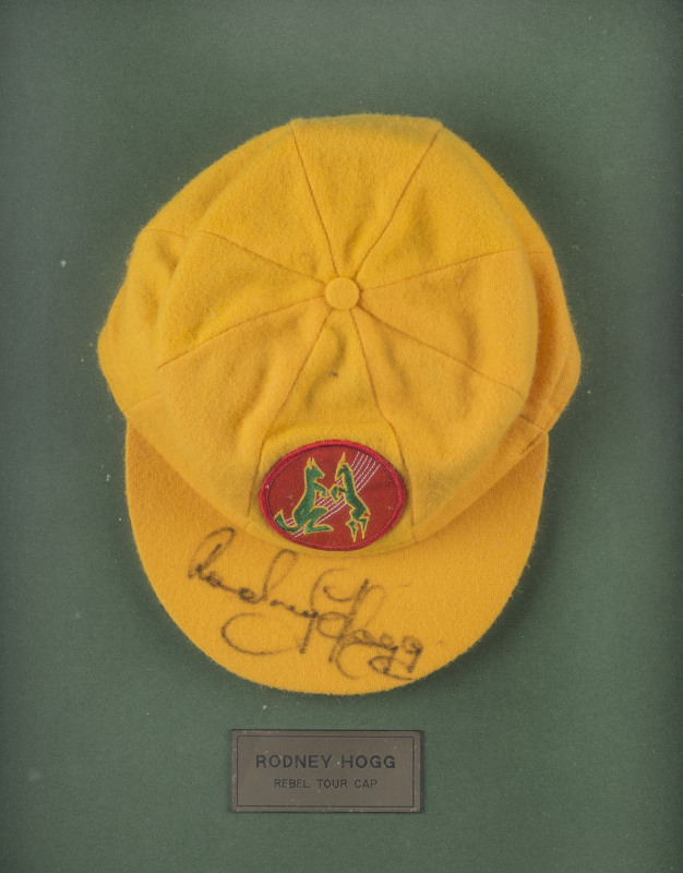 RODNEY HOGG'S REBEL TOUR TEST TEAM CAP, yellow wool with the logo to front (Kangaroo & Springbok on a red cricket ball), signed to the peak by Rodney Hogg. Attractively framed. [Hogg represented Australia in 38 Test matches between 1978 and 1984].