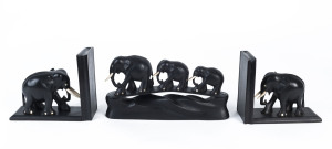 A pair of ebony elephant bookends with ivory tusks (each 12 x 14.5cm), circa 1940s, together with a shelf ornament depicting a family of three ebony elephants with ivory tusks (12 x 23cm). (3 items).