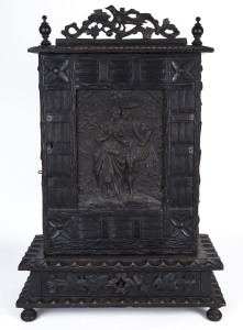 A Black Forest collector's cabinet, ebonised carved timer with embossed panel depicting a romantic couple on the front. 19th Century. 66 x 45 x 20.5cm.