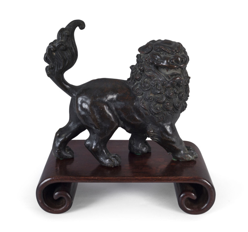 A Chinese bronze temple dog on wooden stand, Qing Dynasty, 19th century, the statue 22cm high, 23cm long