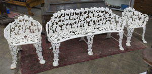 An English cast iron garden seat and two matching chairs with white painted finish, early 20th century, 146cm across the arms