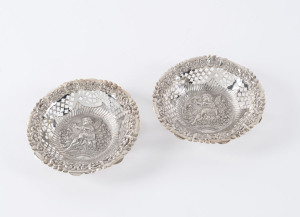 A pair of sterling silver pierced embossed circular dishes decorated with putti, by William Henry Leather of Birmingham, circa 1876. 11.5cm diameter, 80 grams total.