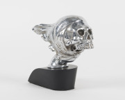 Skull car mascot, chrome on later ebonized timber base, circa 1950, ​mascot 14cm long