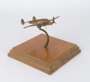 A brass aeroplane ornament on timber stand, circa 1940, 22cm wing span