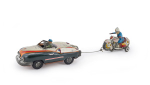 1950's "Atom Star" Space Car with following Cop on Motorcycle, by Yonezawa of Japan. With a friction-like motor in the car which is activated by pulling the motorcycle back by the connecting string. The string "winds" the motor. When the cycle is released the motor starts to turn the car's wheels propelling it forward with a siren sound. As it runs forward, it reels in the cop on his cycle. When the cop gets all the way back to the car, both vehicles stop and the cop can issue the fine.