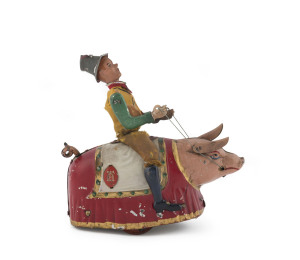 MECHANICAL "PADDY AND THE PIG" BY LEHMANN Lithographed tin Paddy with tin grey top hat and original cloth costume seated upon a circus-decorated pig with red blanket and cream saddle. When wound, Paddy moves around and the pig moves forward and in circles (may need some adjustment). Marked Lehmann model 500, with Patents dated 1903, 1905 and 1907. Height: 15cm (6").