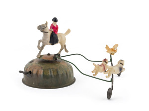 Alps (Japan) celluloid hunter on horseback and dogs chasing a fox; mounted on clockwork metal base. Diameter: 31cm (12").