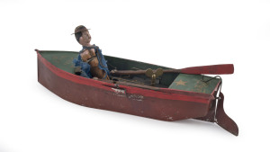 SINGLE OARSMAN by Ives, Patented Feb.1869, by Nathan Warner, tin rowboat is hand painted and stenciled "CARRIE" on stern, features cloth dressed rower with oars in hand, clockwork activates strong rowing action, stenciling very strong. Length (with rudder extended) 33cm (13").