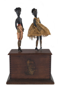 IVES CLOCKWORK DOUBLE JUBA DANCERS, late 1890's black Americana, with clockwork mechanism housed in wooden base, and featuring two wooden figures painted black with outfits. Remnants of the original decal on wooden box stage. Height: 26cm (10.25").